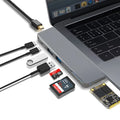 Silver USB-C hub with multiple ports for MacBook Pro, showing USB, card slots, and charging port