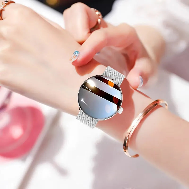 Women's smart watch with circular colour screen and metal strap on a wrist.