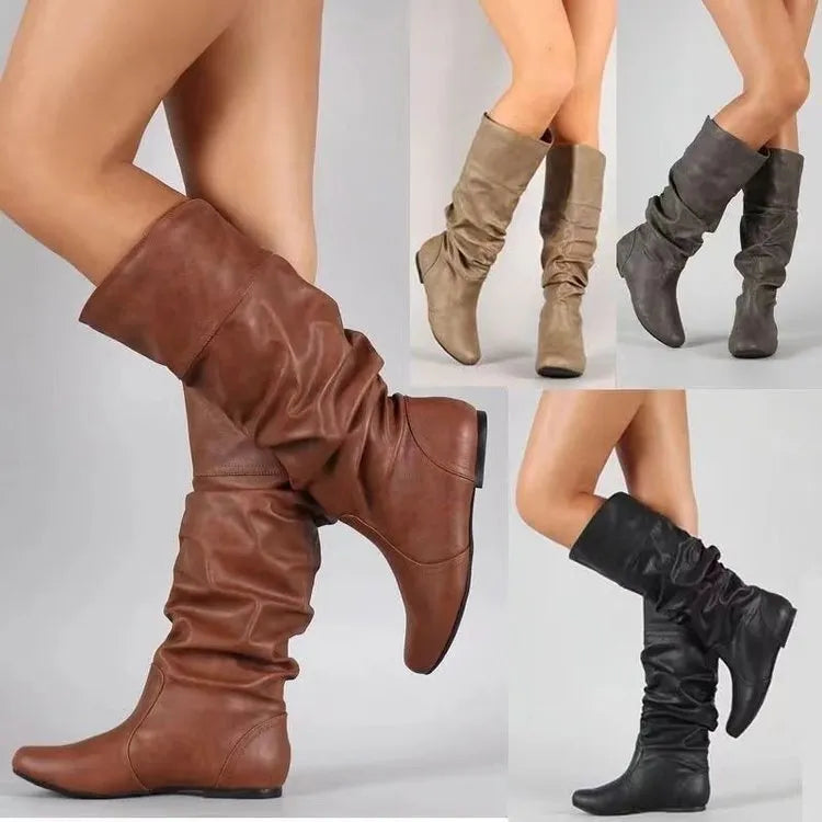 Women's black slip-on long boots with flat heel and round toe on a plain background.