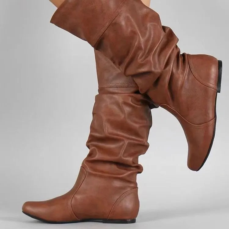 Women's black slip-on long boots with flat heel and round toe on a plain background.