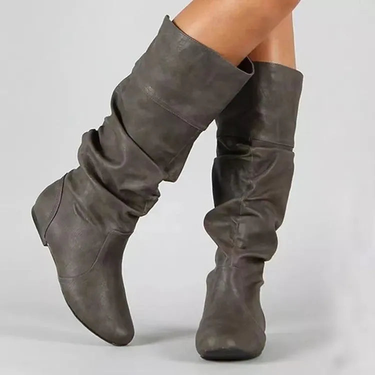 Women's black slip-on long boots with flat heel and round toe on a plain background.