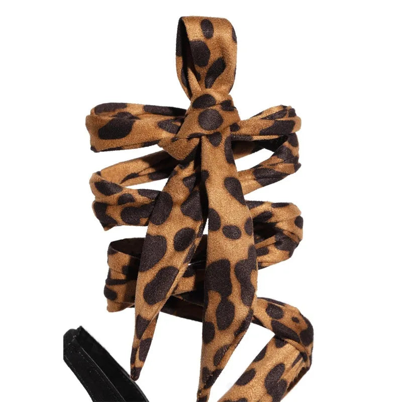 Light brown leopard print women's high heels with cross straps and a thin high heel.