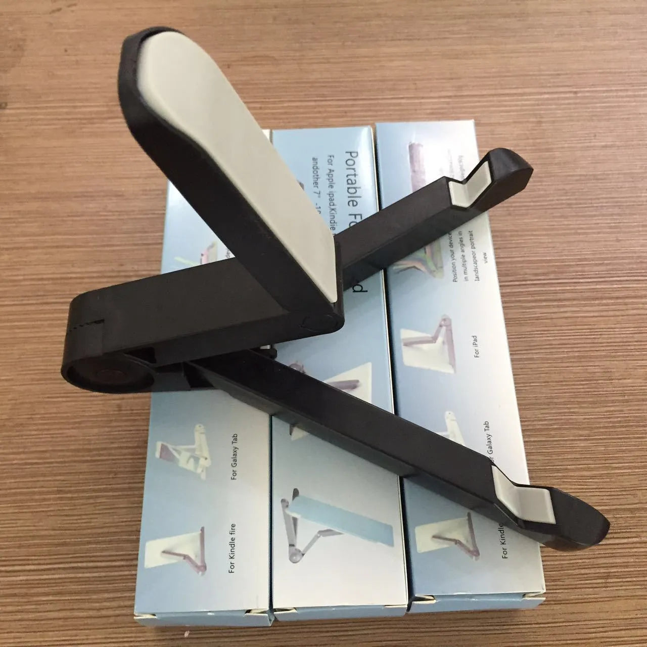 Black foldable tablet holder standing upright with a tablet device resting on its non-slip rubber surface.