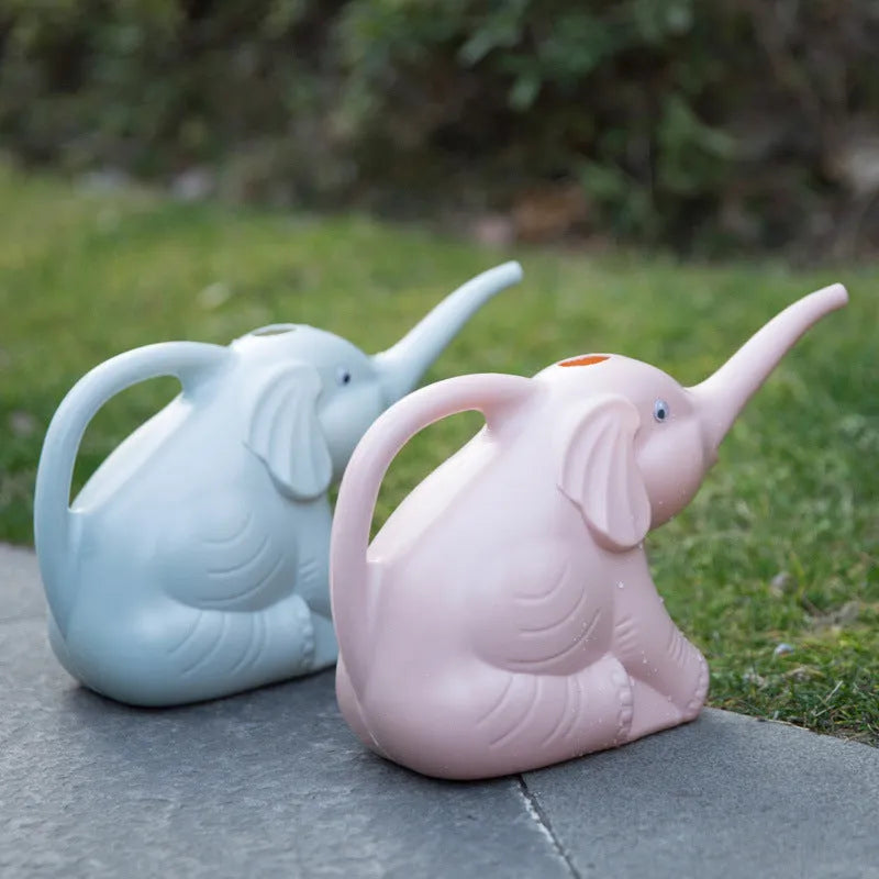 Pink baby elephant-shaped watering can with a long nozzle and bottle-shaped handle on a table.