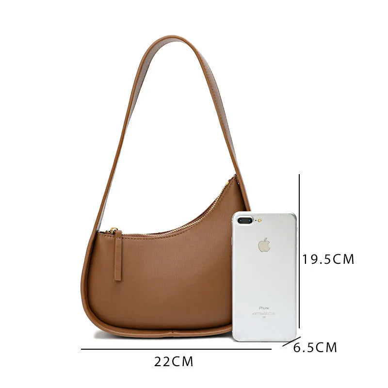 Women's half moon shaped leather shoulder bag in light brown with an adjustable wide strap.