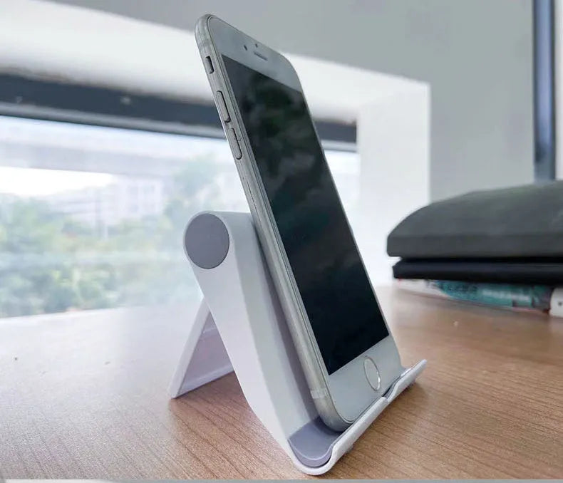 Black folding mobile phone and tablet stand with multi-angle adjustment on wooden table