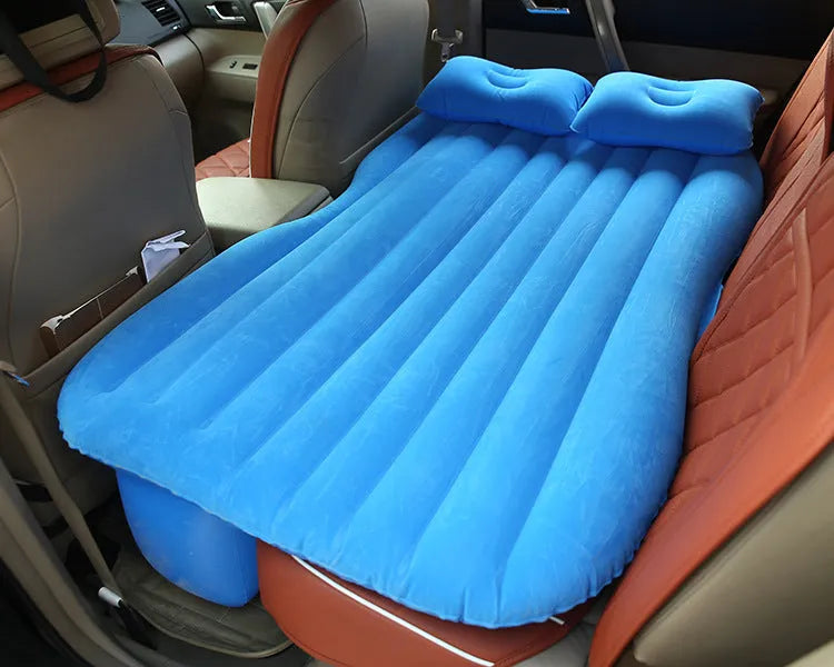 Black inflatable car bed with flocked material and two pillows, set up in a car's rear seats.