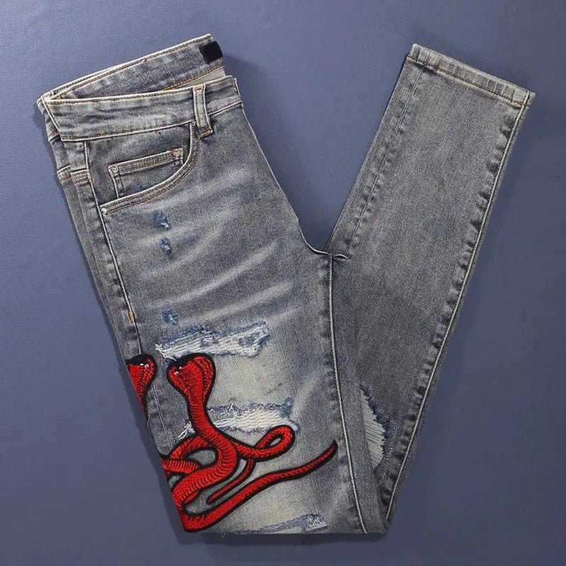 Men's slim fit jeans with a washed-out faded finish and embroidered patch details on the leg.