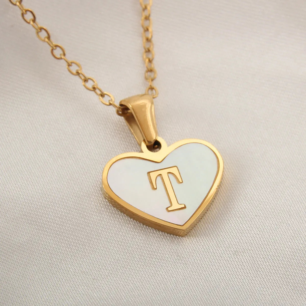 Gold heart necklace with white shell detail and personalised initial letter on adjustable chain
