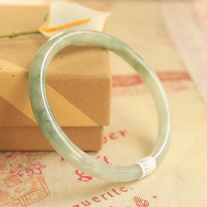 Green jade waxy geometric bracelet with Chinese-style design on a wrist.