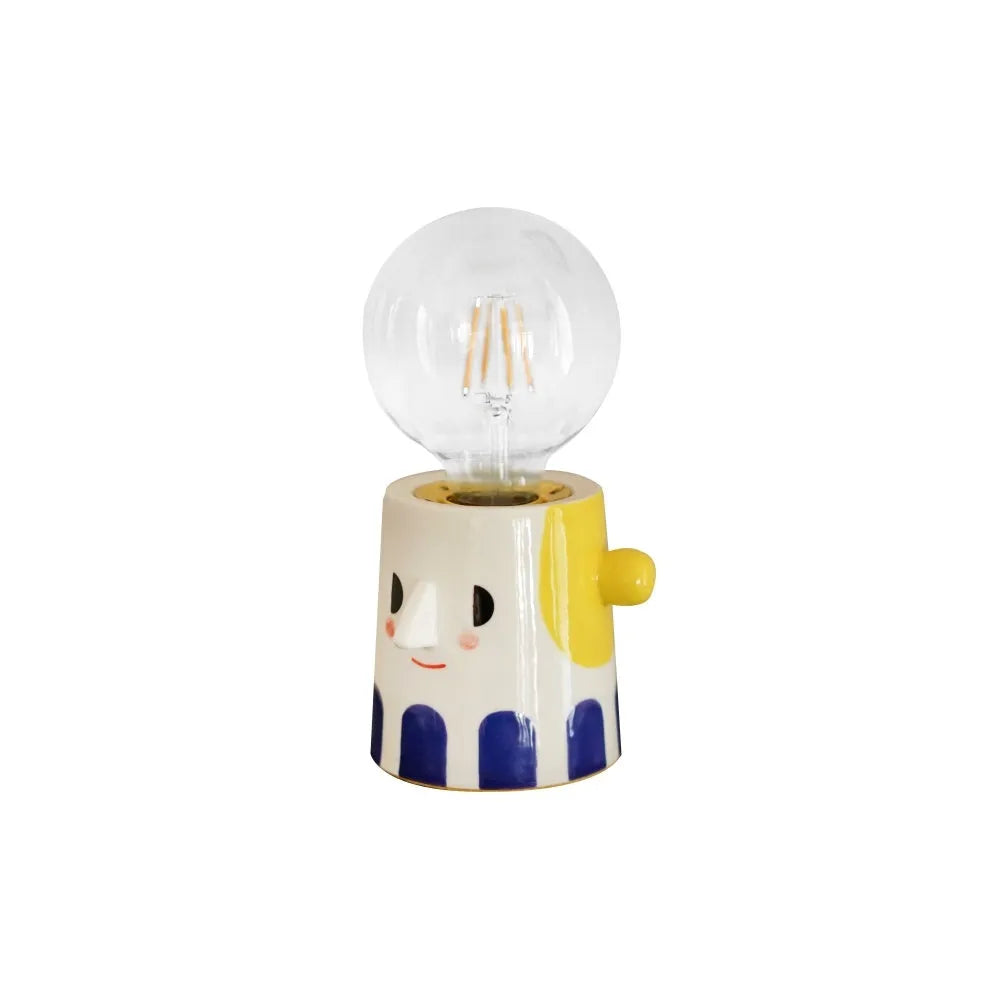 Handmade ceramic table lamp with a spherical ball headlight design on a bedside table.