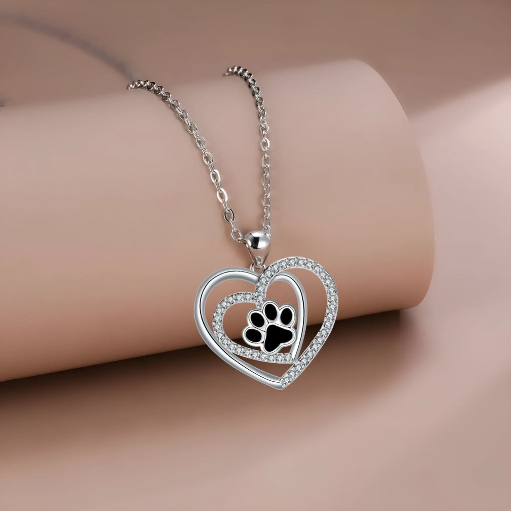 Women's dog paw print necklace with heart-shaped pendant on a cross chain.