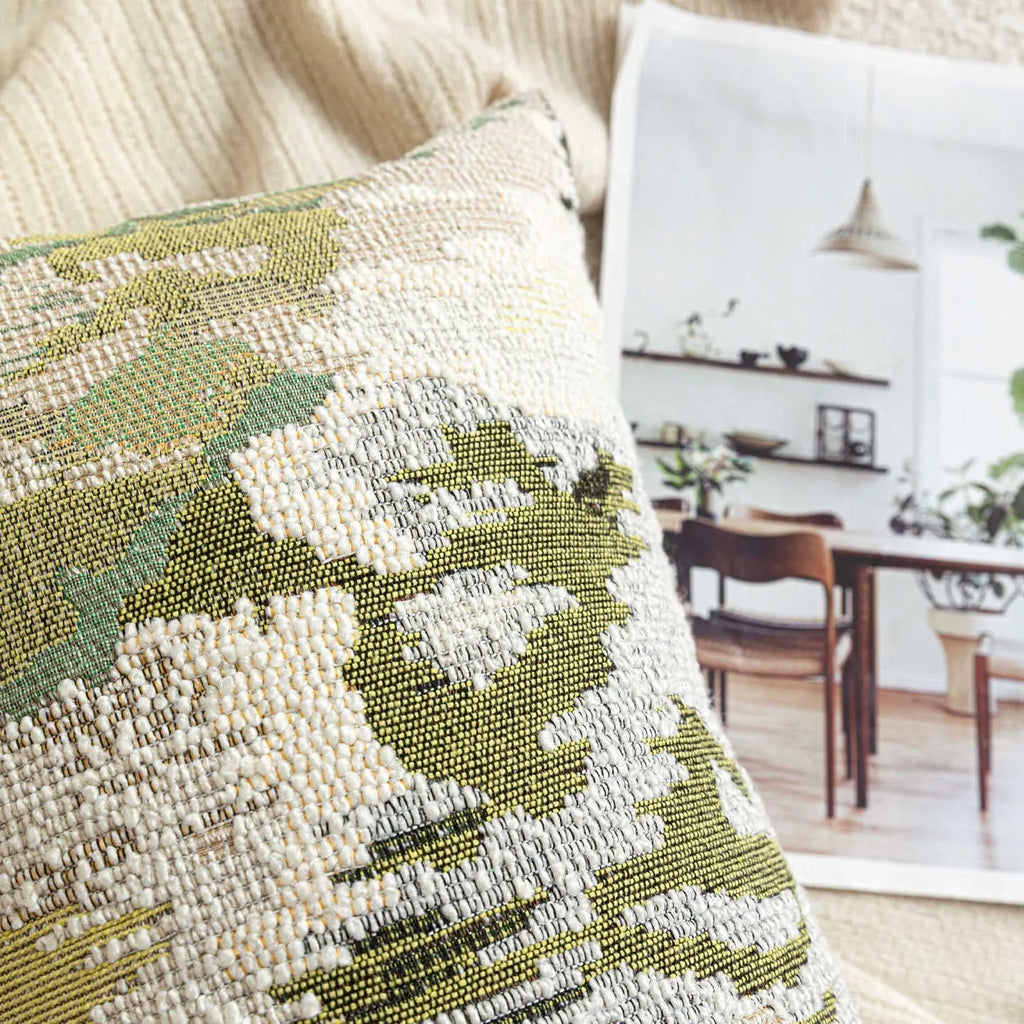 Green abstract floral wool blend decorative cushion on a neutral background.