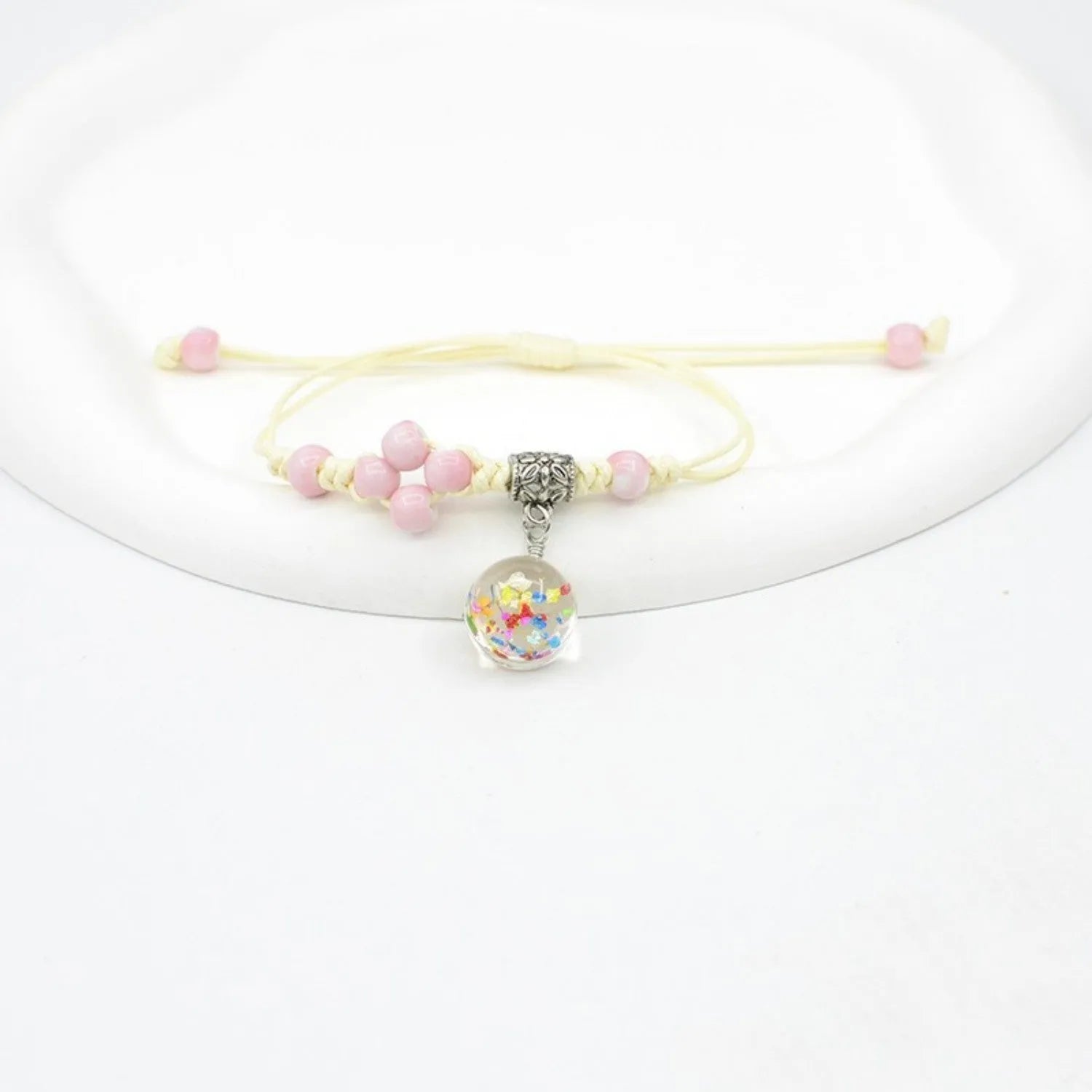 Glass bracelet with large colourful beads containing real dried flowers, on a white background.