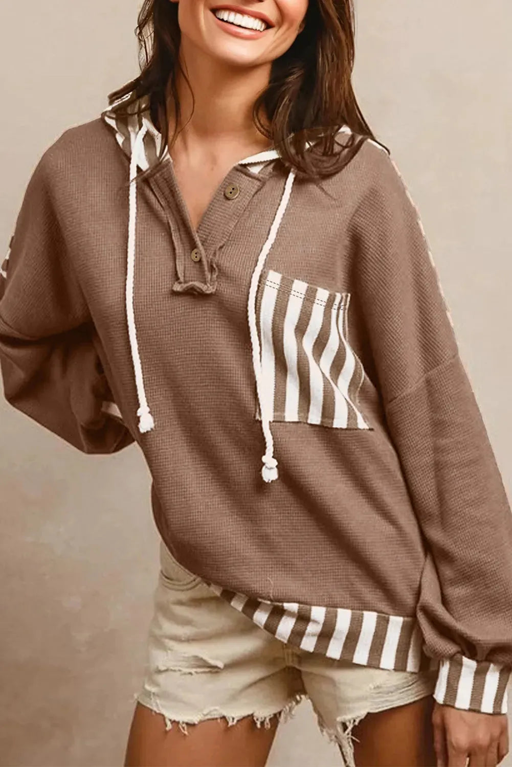 Straw yellow hoodie with waffle texture fabric, striped patchwork design, and button neck closure.