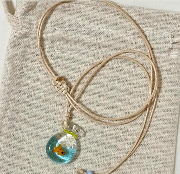 Women's necklace with coloured glaze joker charm on cotton linen chain in small fish lucky bag colour