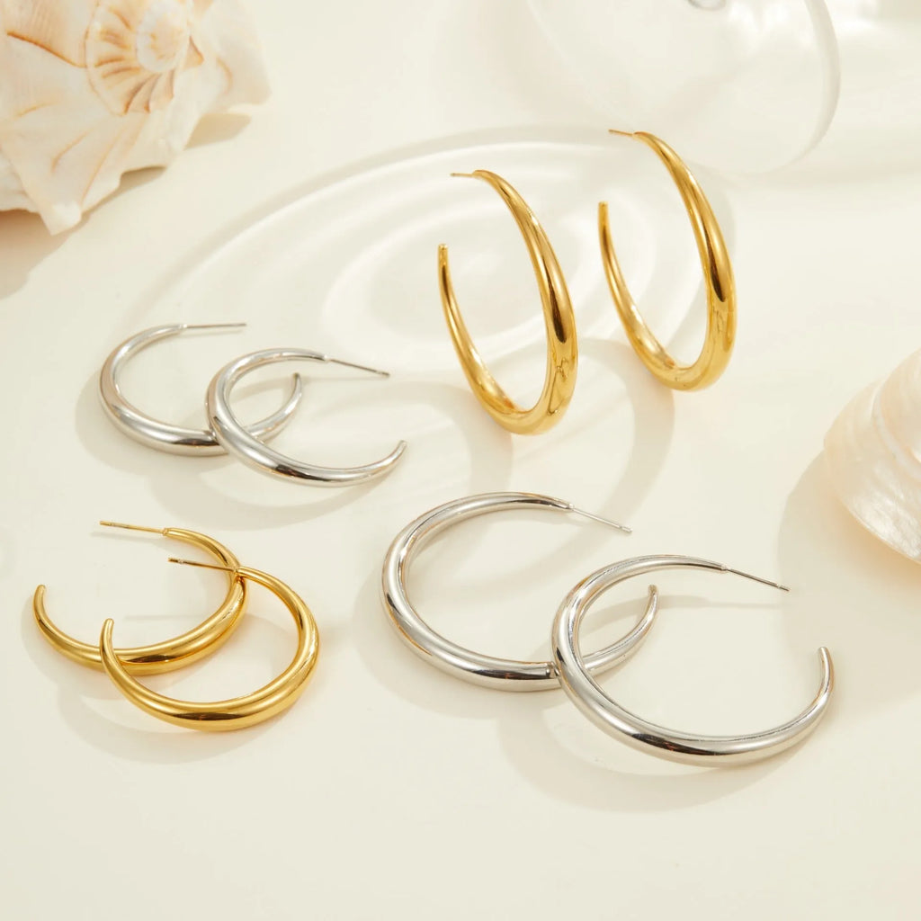 A pair of simple round titanium steel hoop earrings in a gold finish on a white background.