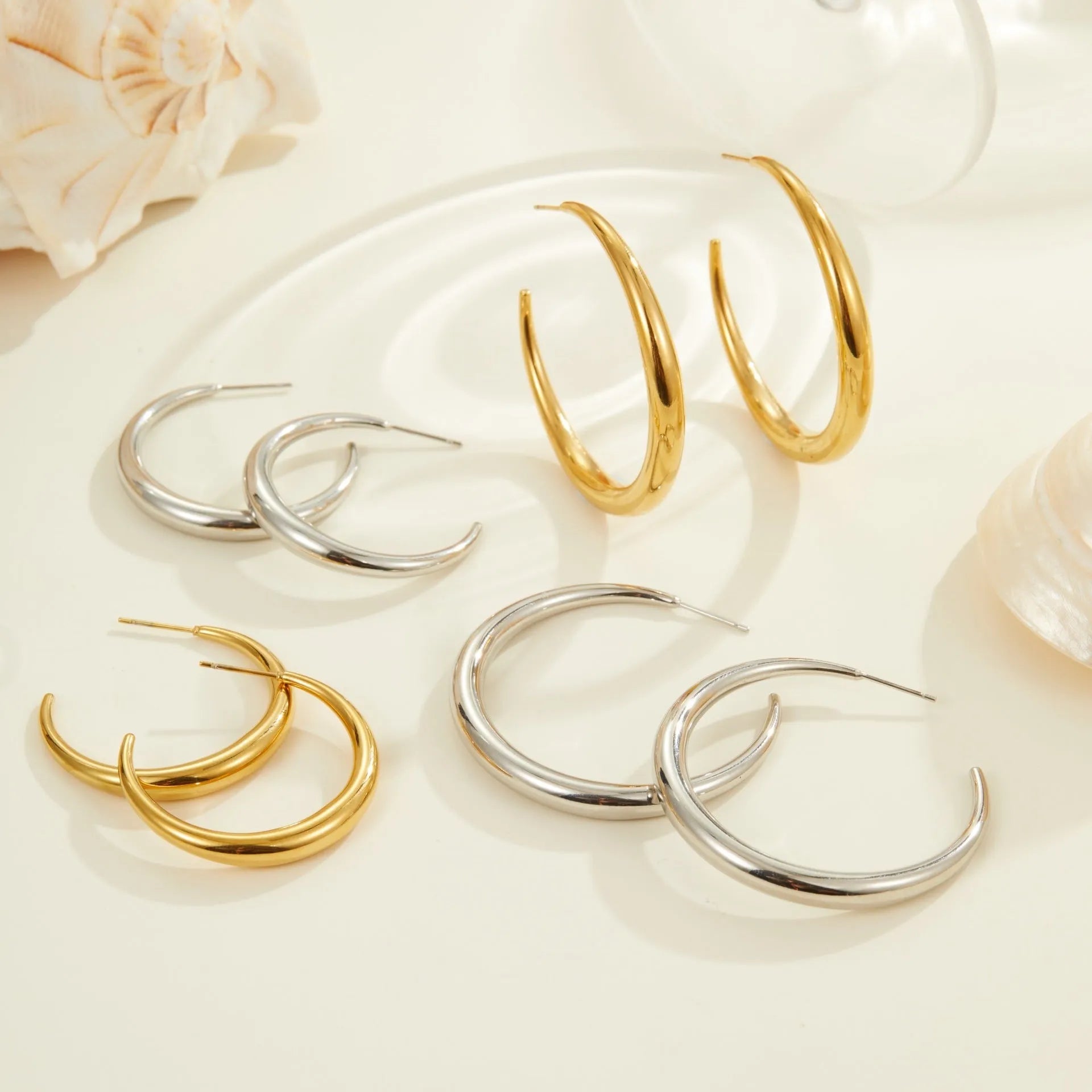 A pair of simple round titanium steel hoop earrings in a gold finish on a white background.