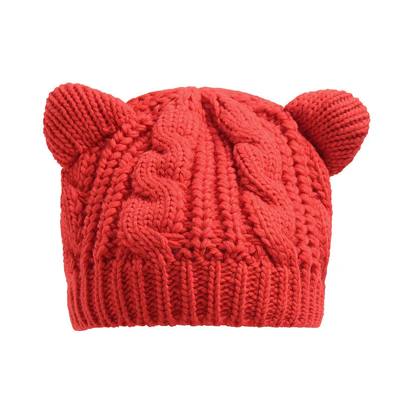 Handmade red knitted beanie with 3D cat ears on a white background