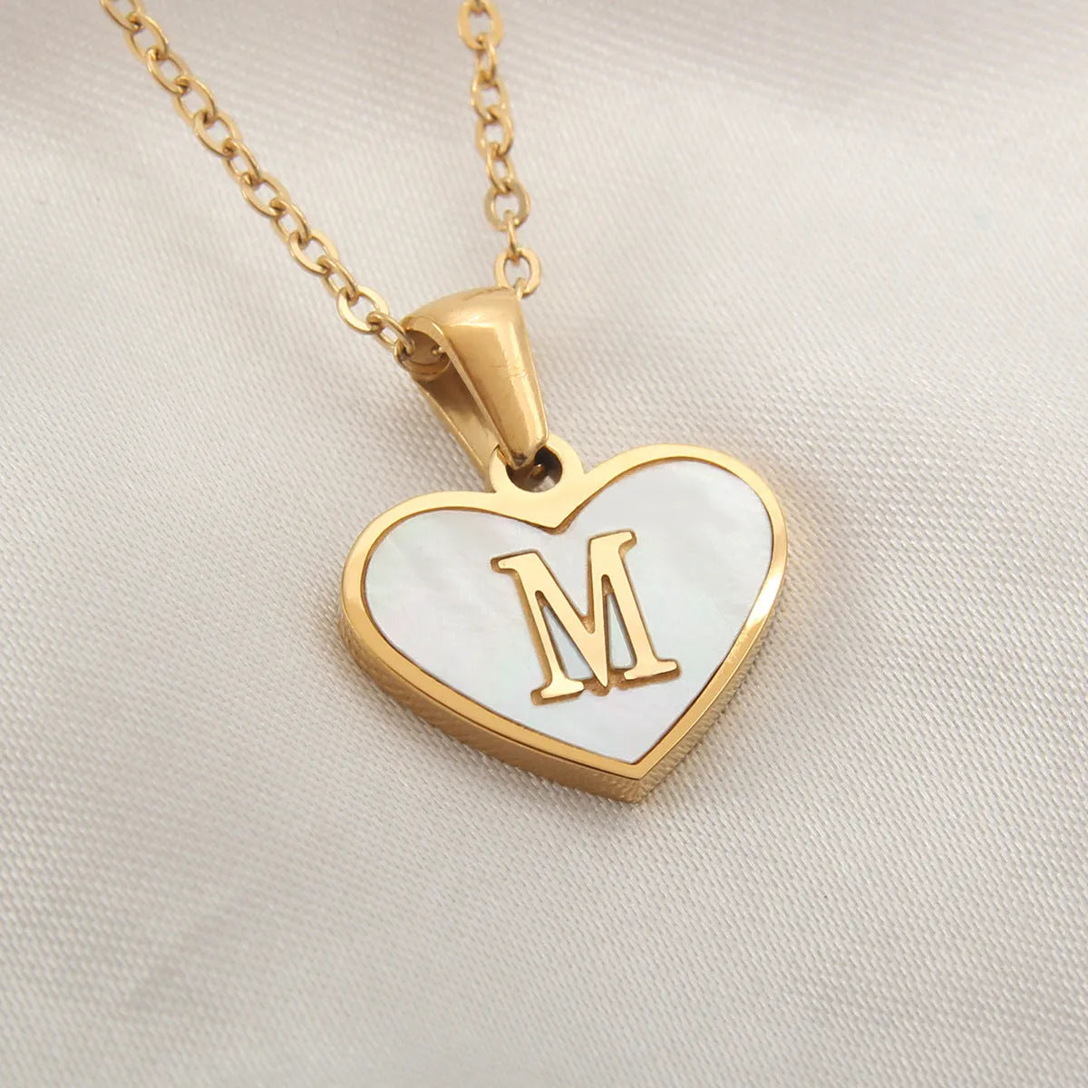 Gold heart necklace with white shell detail and personalised initial letter on adjustable chain