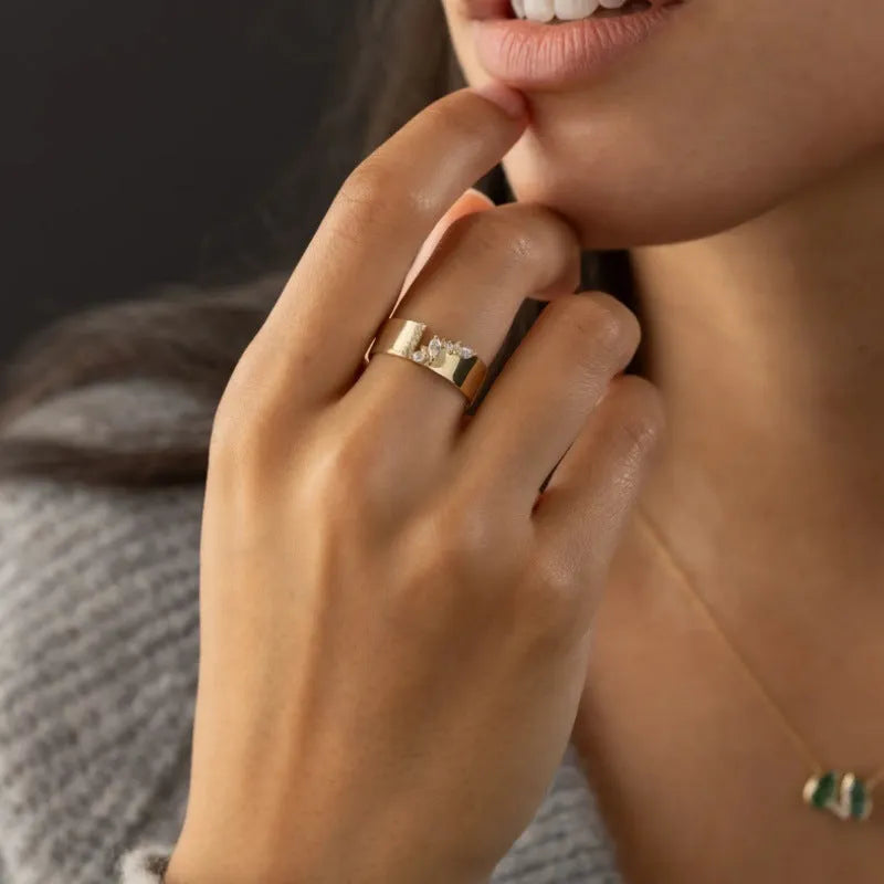 Gold electroplated women's ring with a shining zircon stone, shown on a finger.