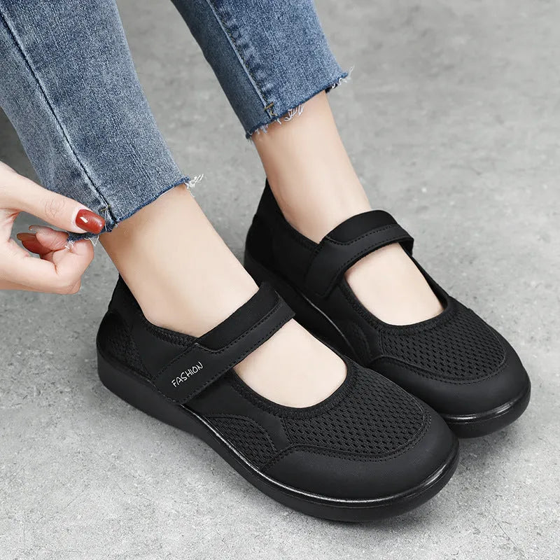 Women's grey casual slip-on shoe with mesh upper and Velcro strap on a flat sole.