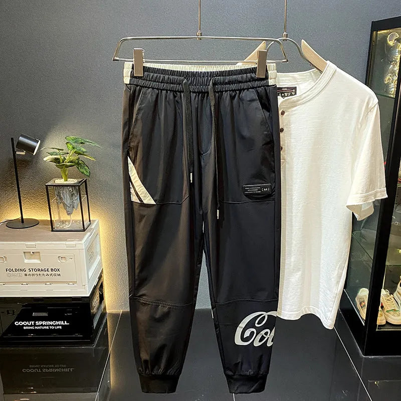 Men's solid black cotton cropped trousers with elasticated ankle band cuffs laid flat.