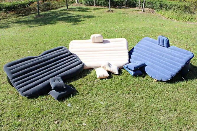 Black inflatable car bed with flocked material and two pillows, set up in a car's rear seats.