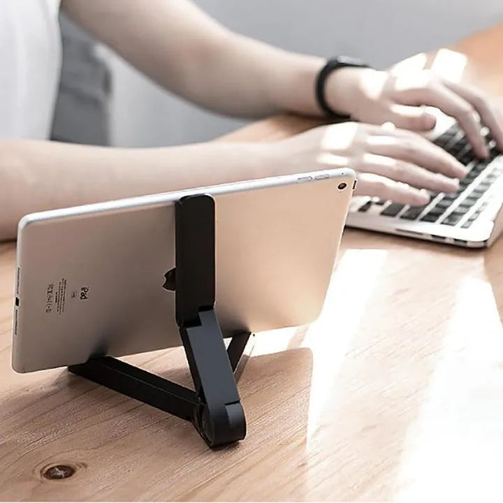 Black foldable tablet holder standing upright with a tablet device resting on its non-slip rubber surface.