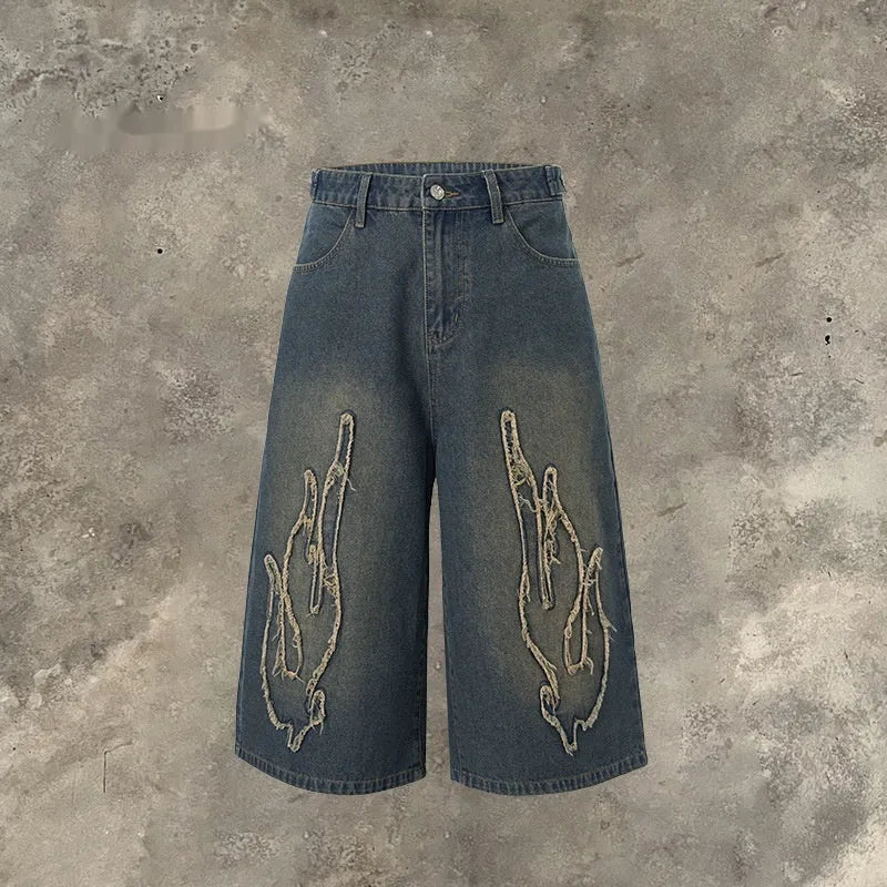 Men's black denim shorts with flame embroidery patch on leg, cropped straight cut style