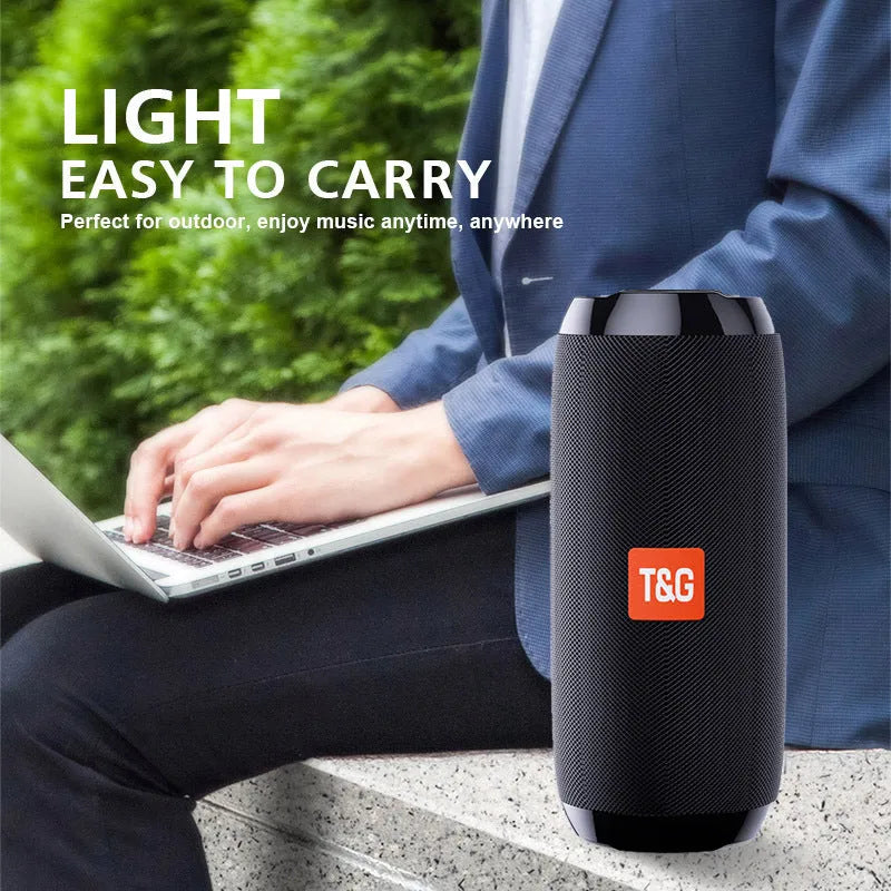 Black portable IPX5 waterproof Bluetooth speaker with mesh grille on a rocky outdoor surface
