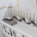 Soft spandex velvet braided knot crib bumper in a neutral colour, shaped around a cot.