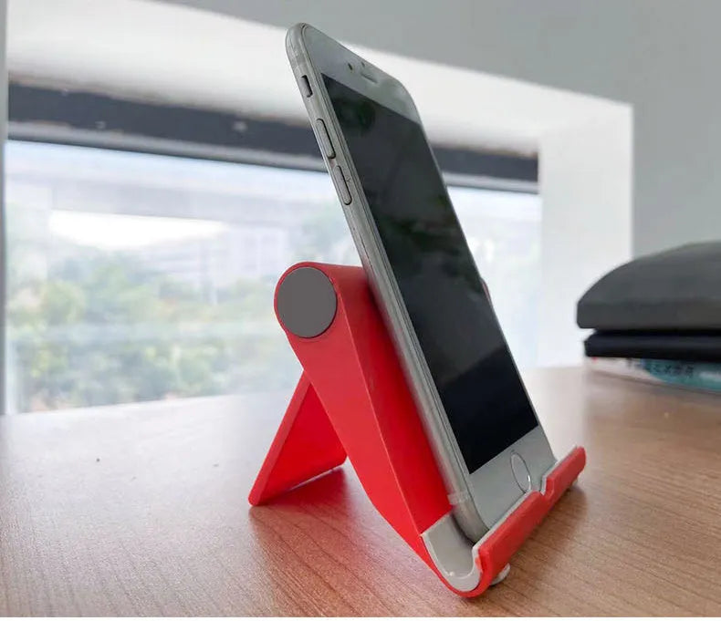 Black folding mobile phone and tablet stand with multi-angle adjustment on wooden table