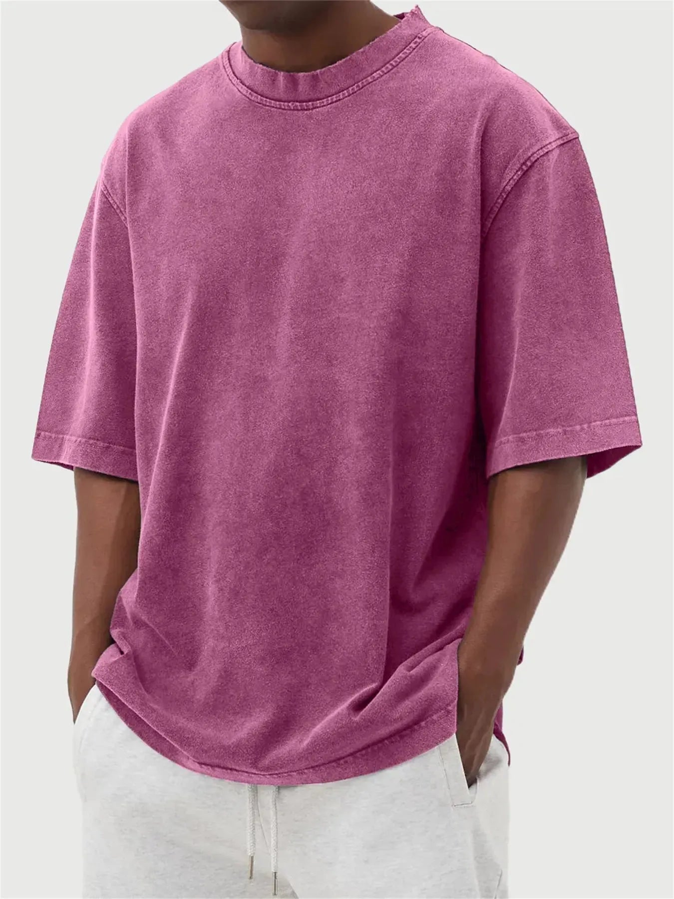 Man wearing a loose-fit, stone-washed distressed pullover T-shirt in a solid colour.
