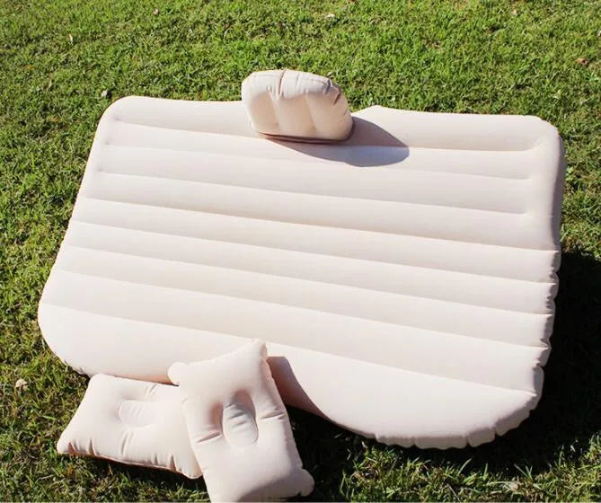 Black inflatable car bed with flocked material and two pillows, set up in a car's rear seats.