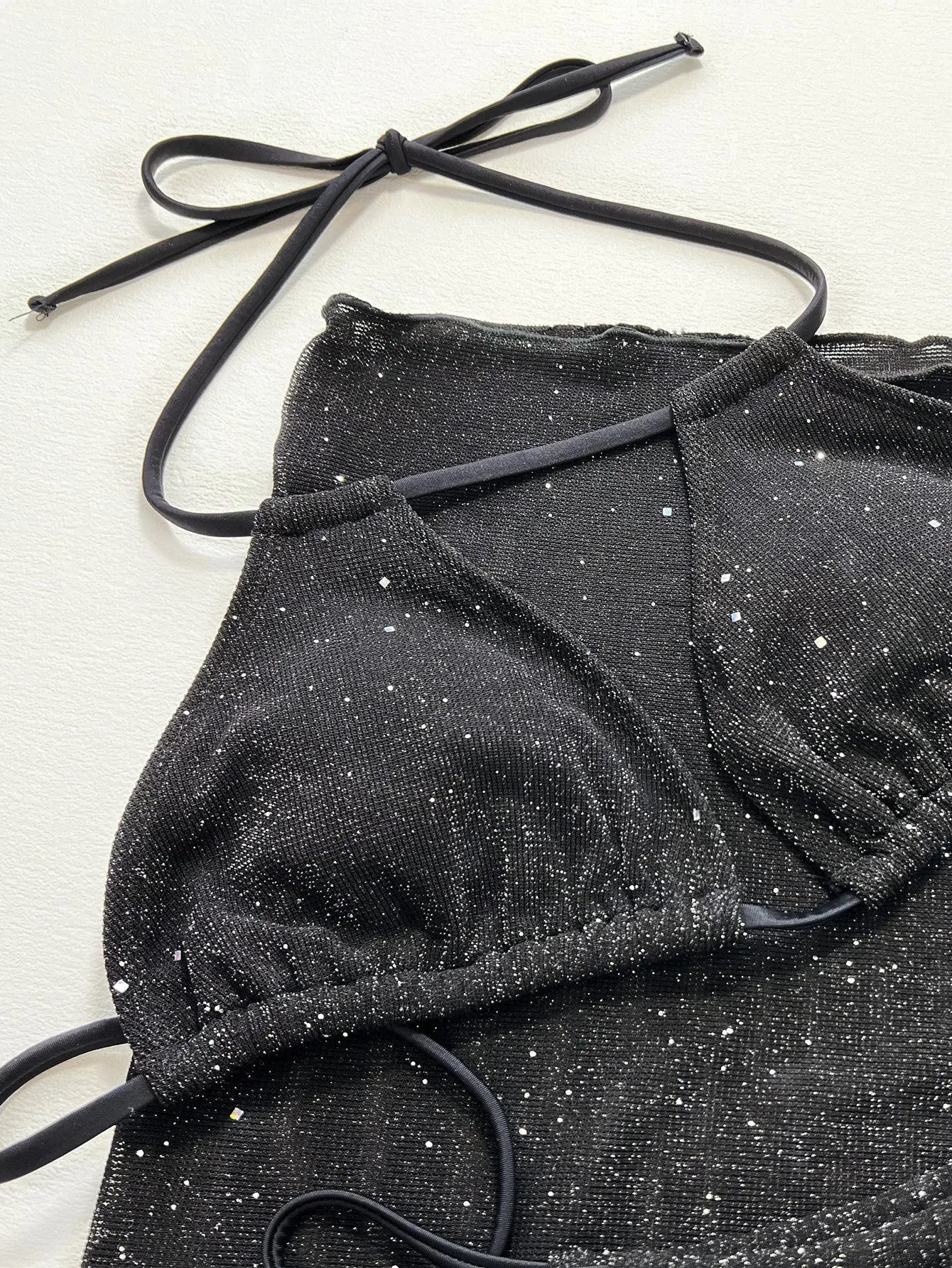 Black three-piece bikini swimsuit set with top and shorts on a mannequin