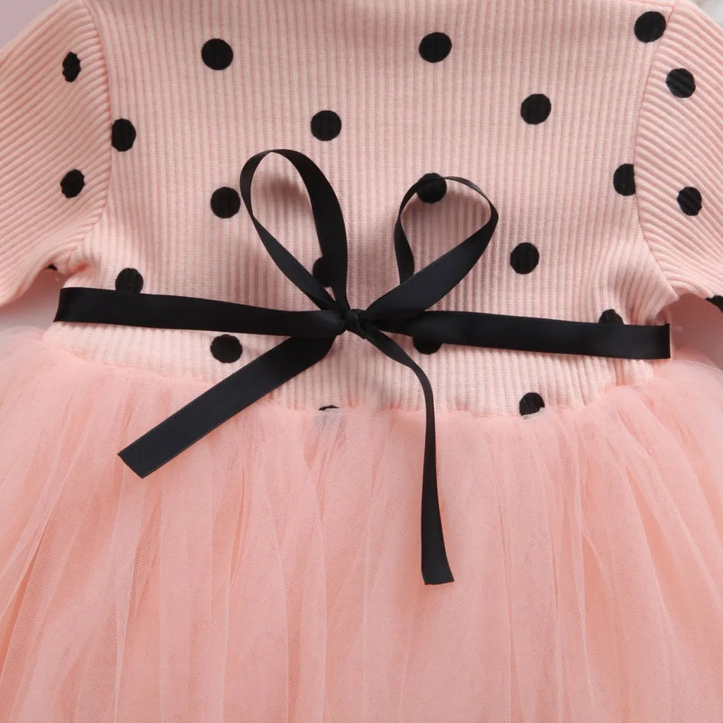 Baby girl wearing a long sleeve lace and tutu dress in pink, suitable for a birthday party.