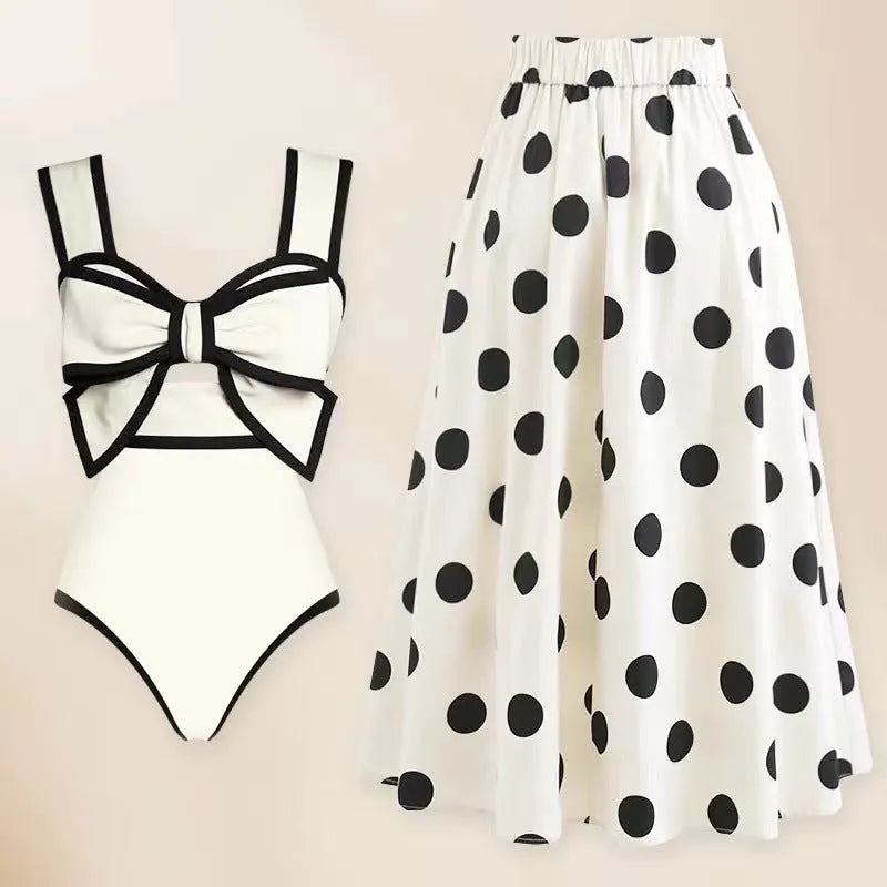 Women's black one-piece swimsuit with a white round skirt and a bow detail at the front.