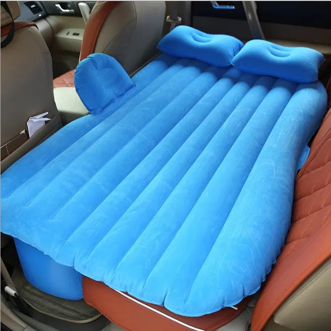 Black inflatable car bed with flocked material and two pillows, set up in a car's rear seats.