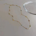 Square geometric clavicle chain necklace in gold tone with artificial crystal details on a model.