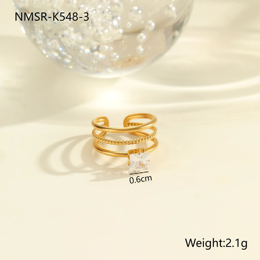 Gold-plated geometric stainless steel ring with inlaid zircon stones on a white background.