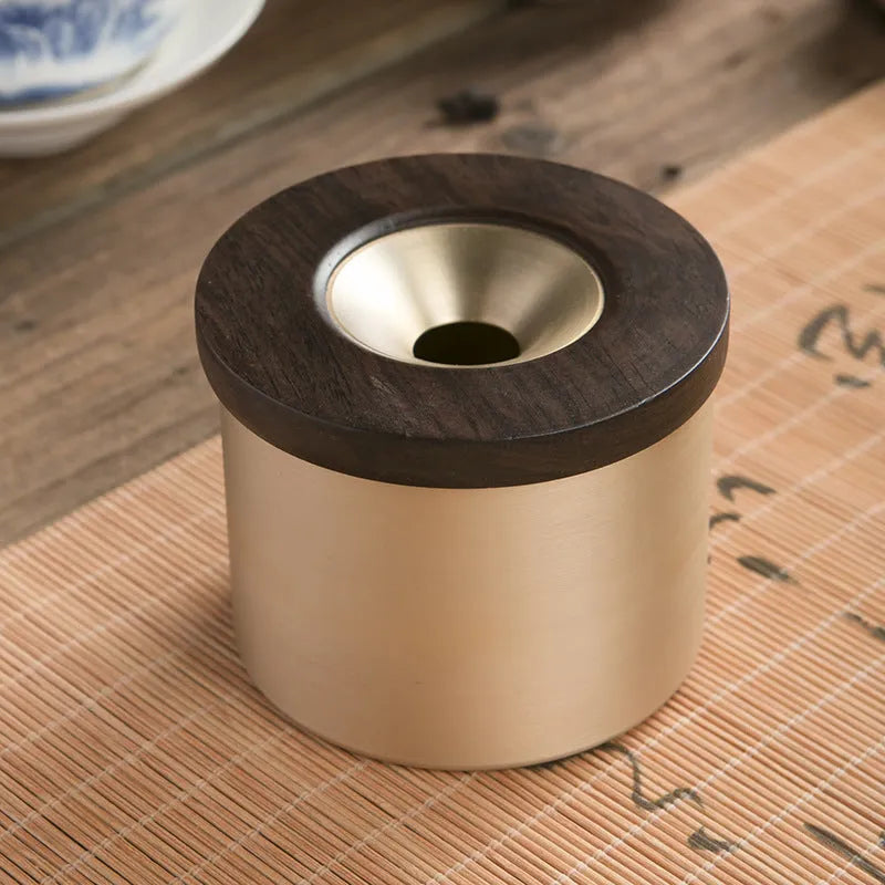 Brass ashtray with wooden lid showing central hole design for ash collection