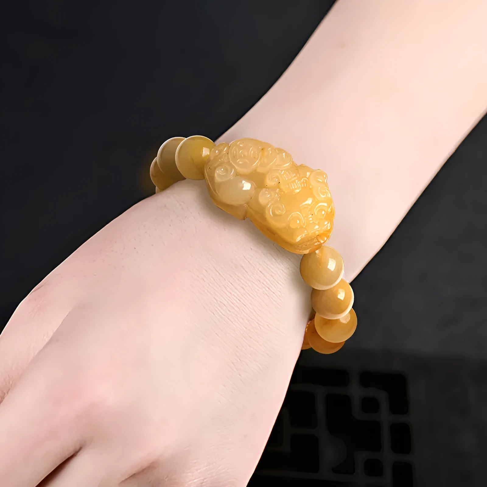 Carved Golden Thread Jinsi Jade bracelet with money motif on adjustable cord, shown in two bead sizes.