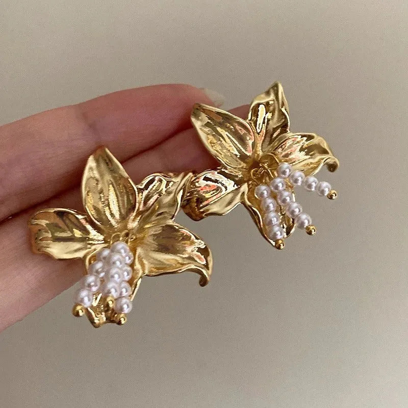 Gold H1795 metal flower earrings with a pearl centre, showing exaggerated floral shape and niche style.