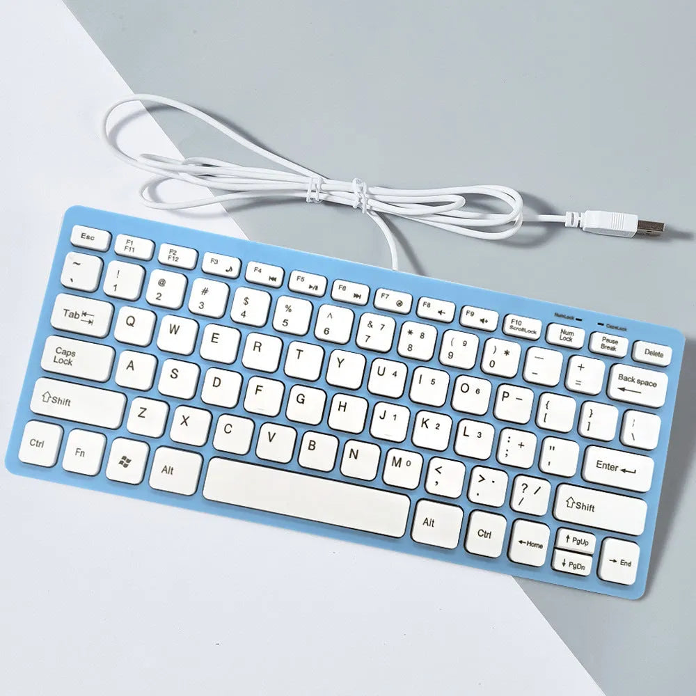Compact USB wired keyboard in black, white, pink, or blue colour options on a desk.