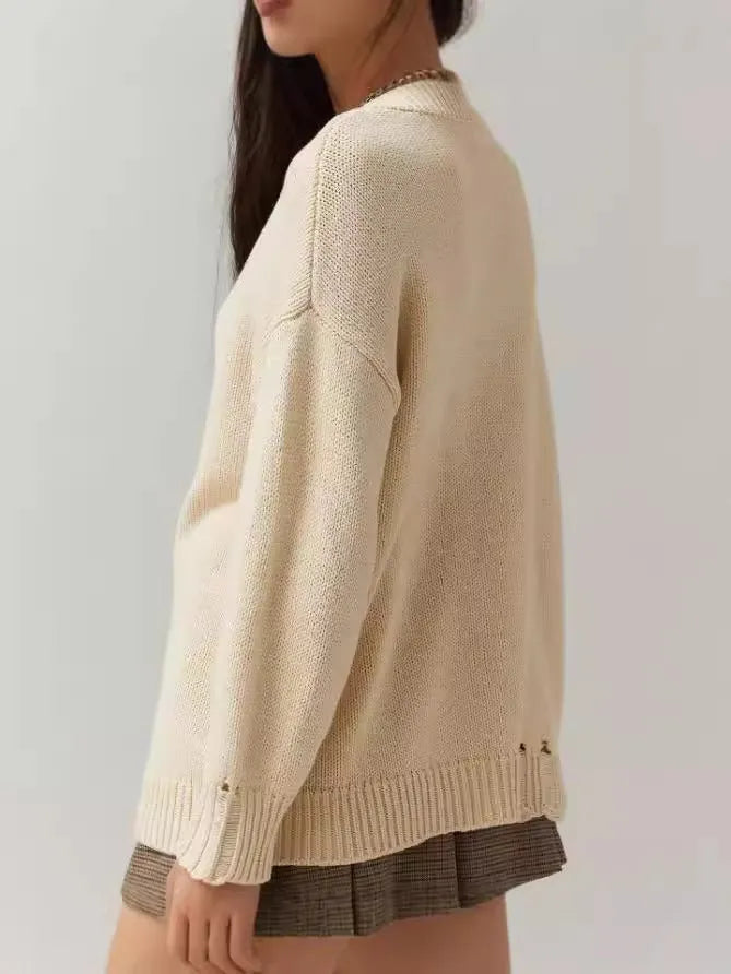 Women's beige loose-fit acrylic Jacquard knit sweater with round neck and long sleeves laid flat.