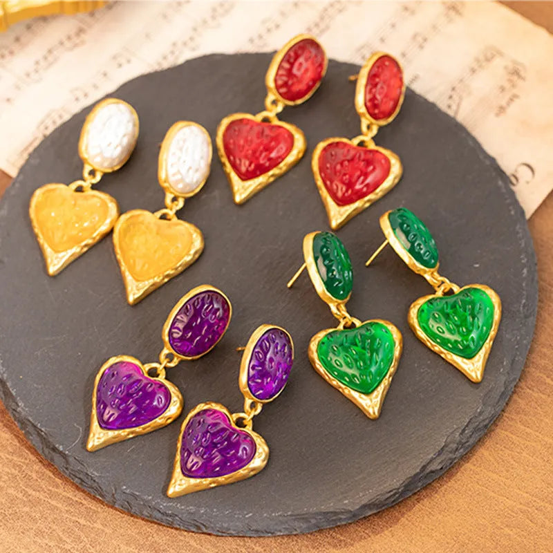 A pair of oval-shaped, pleated love heart stud earrings in alloy, shown in various colours.