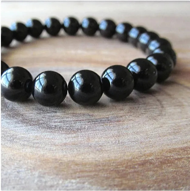 Close-up of a women's geometric bracelet with black agate beads on a black elastic cord.