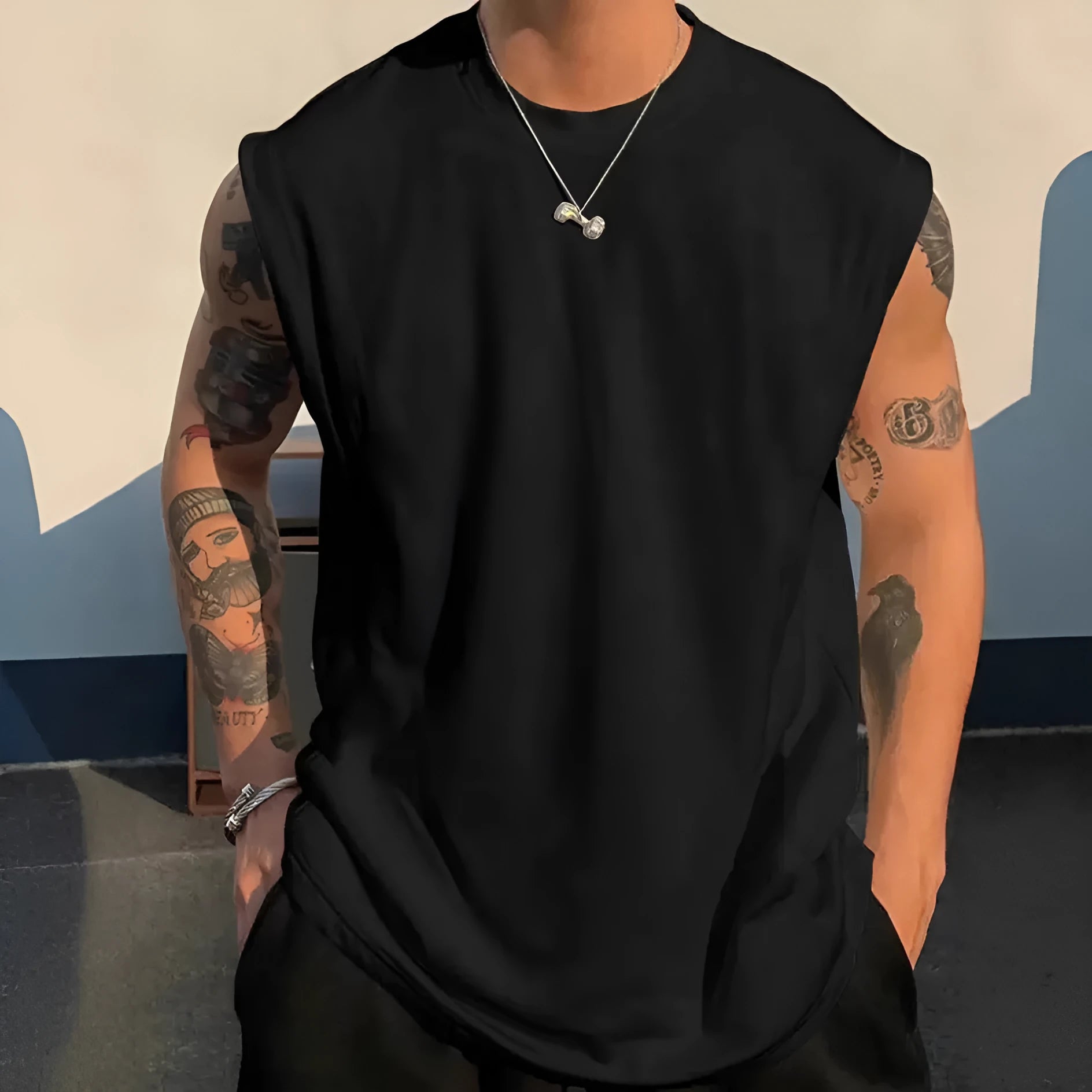 Man wearing a loose, solid-colour cotton sleeveless tank top in a casual setting.