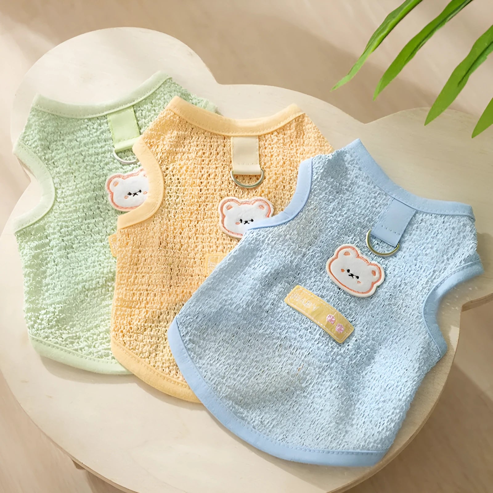 Green knitted cat clothes with a hollowed-out design and a cartoon bear patch.